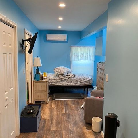 Finished addition bedroom with blue walls, recessed lights and wide-plank flooring