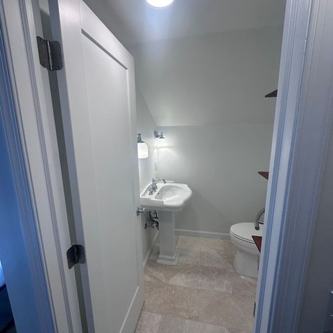 Powder room with a pedestal sink and a stone tile floor