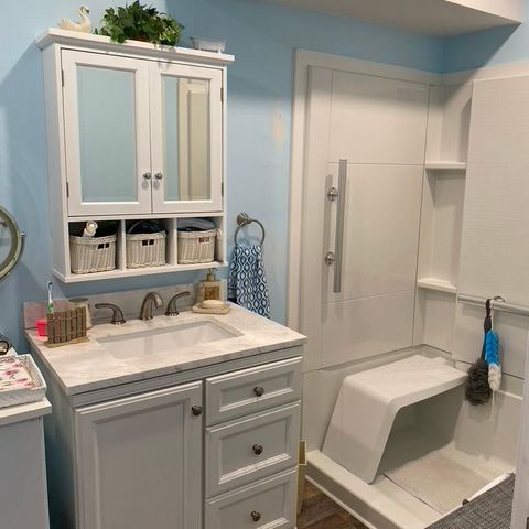 White vanity and storage cabinet beside a walk-in shower