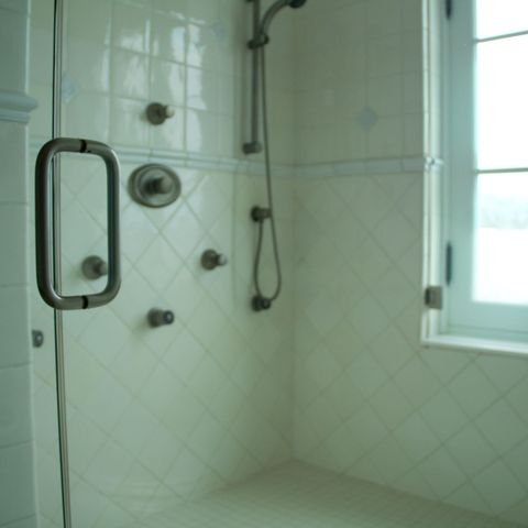 Glass-enclosed tile shower with body sprays and a window