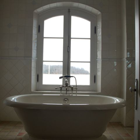 Freestanding tub under an arched window, framed by open doors