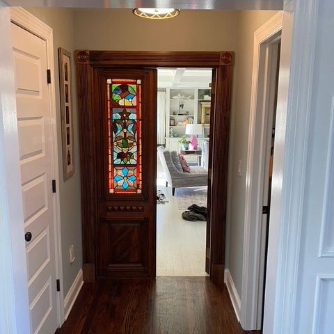 Hallway leading to a stained wood door with a leaded-glass panel