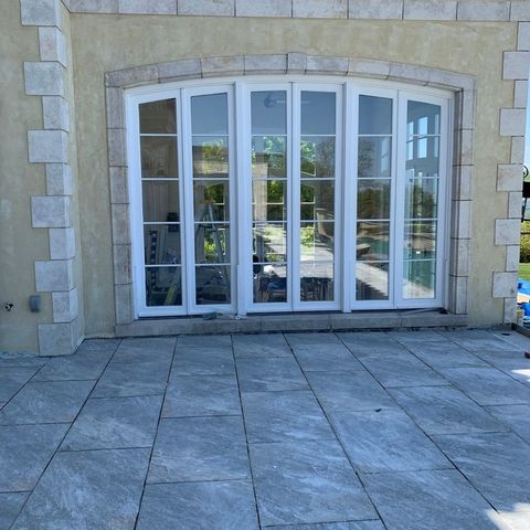 Arched run of French doors opening onto a stone patio
