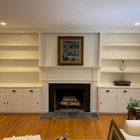 Painted built-in bookshelves and cabinets on both sides of a fireplace