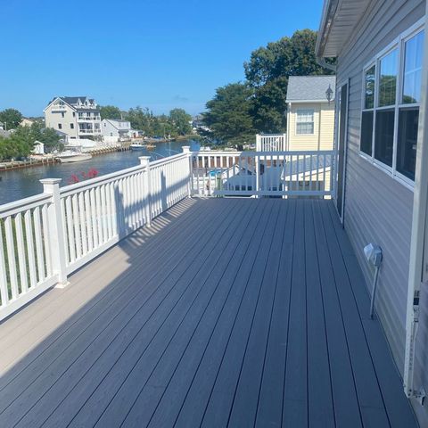 Grey composite deck with white railings running along the water