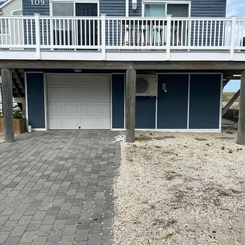 Raised deck with white railings across the front of a blue shore house