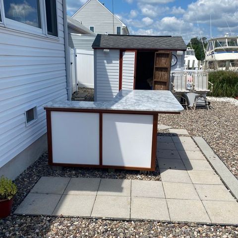 Outdoor bar with a marble top and mahogany trim beside the water