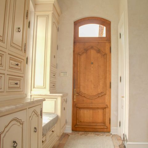 Carved arched wood door beside paneled cream cabinetry and a window seat