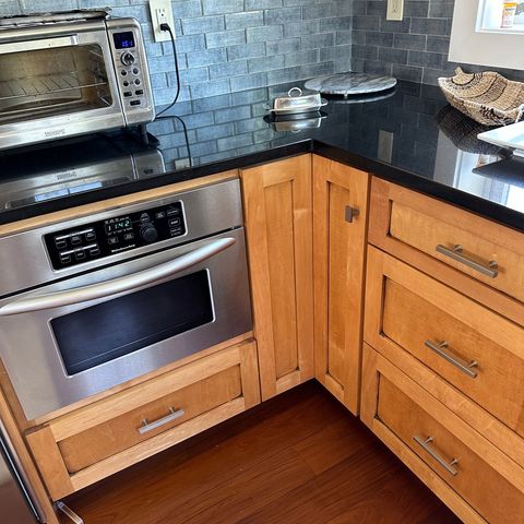 Maple shaker cabinets with a black granite counter and a blue tile backsplash