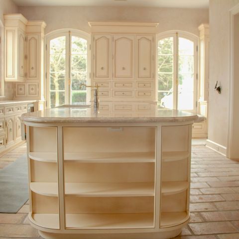Kitchen island with curved open shelving, arched windows behind