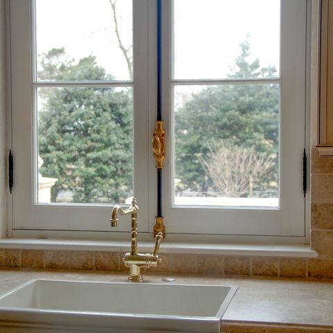 Brass bridge faucet and farmhouse sink under a double window
