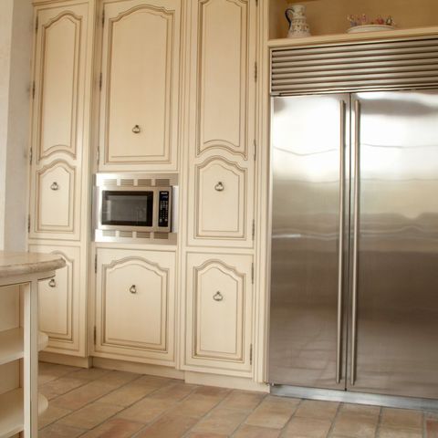 Built-in stainless refrigerator framed by cream panel cabinetry