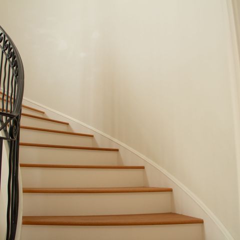 Curved stair with white risers, oak treads and a wrought-iron railing