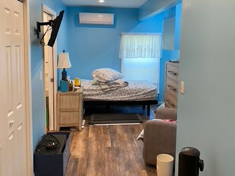 Finished addition bedroom with blue walls, wide-plank flooring and a mini-split