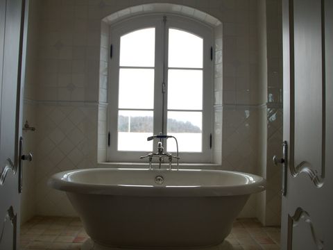 Master bath with a freestanding tub under an arched window