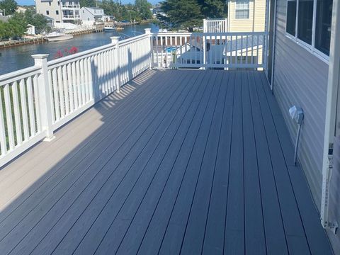 Grey composite deck with white railings along the water