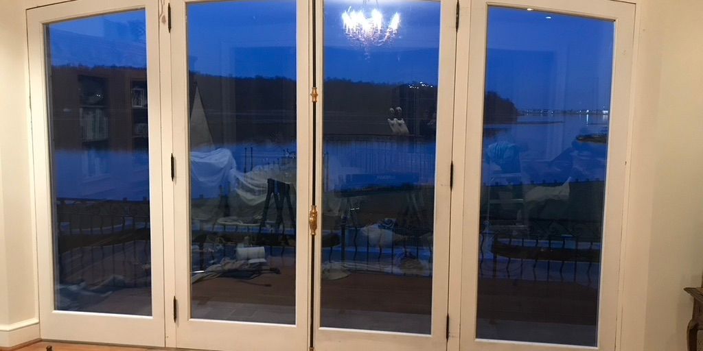 Folding glass doors opening onto the water at dusk