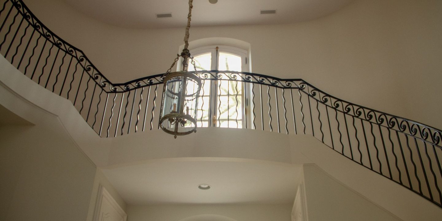 Sweeping staircase with a wrought-iron balcony rail